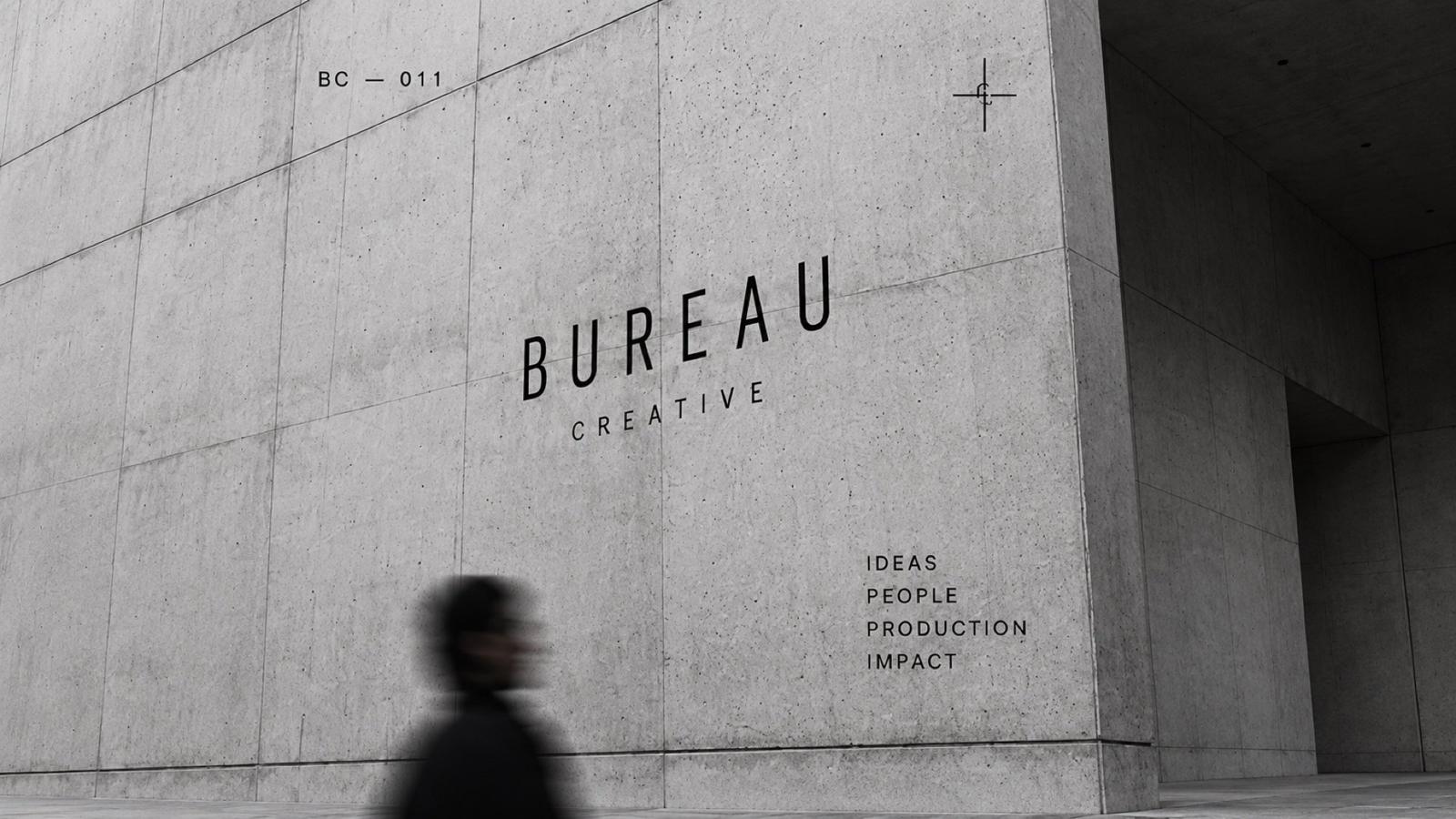 A Bureau poster on a street wall, a passer-by in shadow