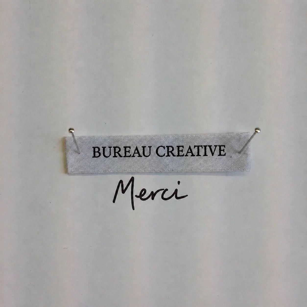 A label reading Bureau Creative, pinned at both ends, with Merci handwritten below