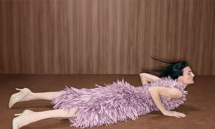 A model lying in a lilac feathered dress
