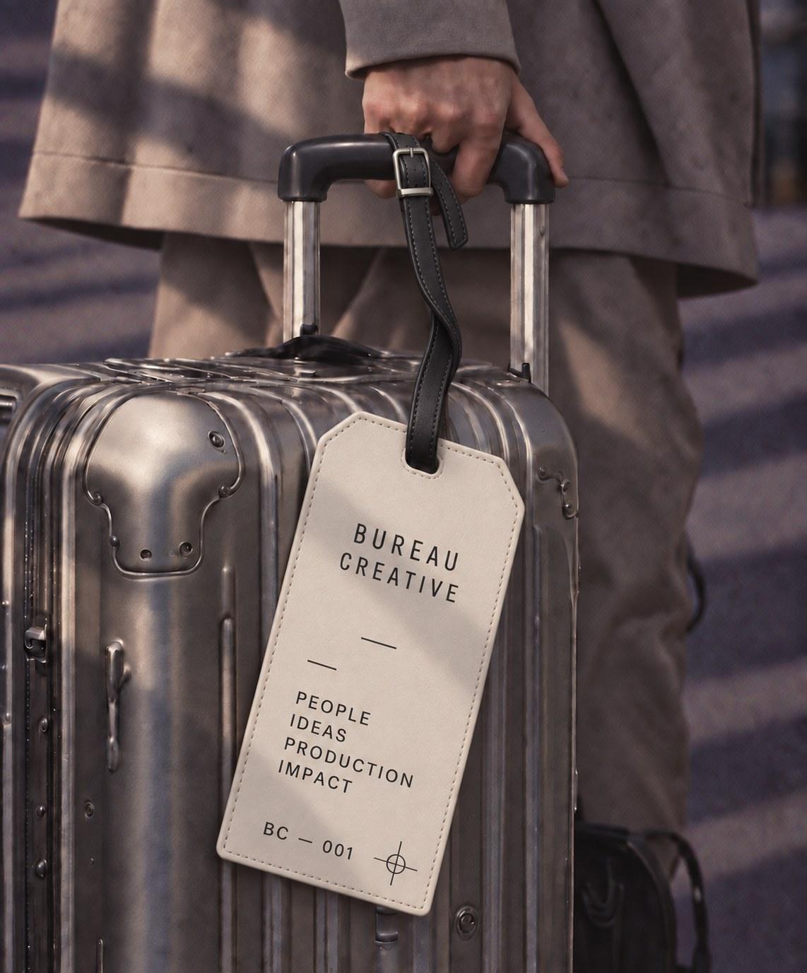 A steel suitcase with a leather Bureau Creative luggage tag