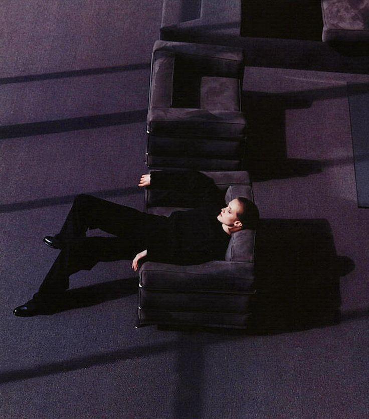 A woman lying on a velvet sofa in a dim room